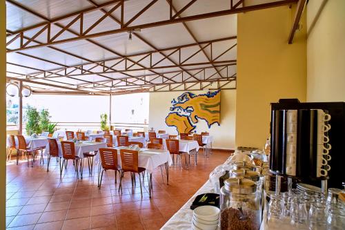 una sala da pranzo con tavoli e sedie bianchi di Veronica Hotel a Kato Daratso