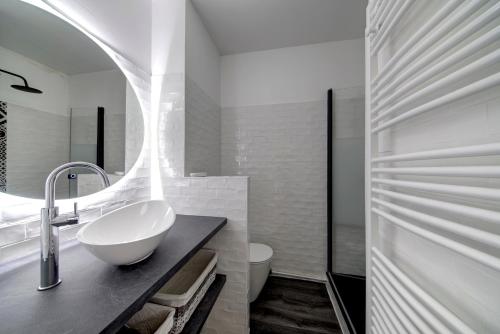 une salle de bain blanche avec un lavabo et un miroir dans l'établissement Le Port de la Lune - Vue panoramique sur les Quais, à Bordeaux