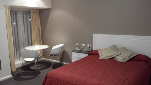 a bedroom with a red bed and a table and chairs at McLaren Vale Motel & Apartments in McLaren Vale
