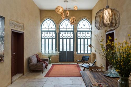 a living room with large windows and a table at La Maison des Sources in ‘Ayn Zḩaltā