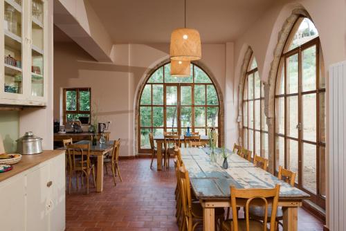 a dining room with a long table and some windows at La Maison des Sources in ‘Ayn Zḩaltā