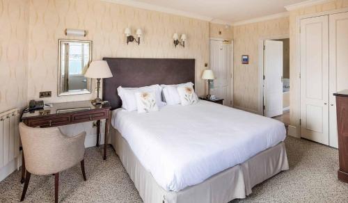 a bedroom with a large white bed and a desk at Somerville Hotel in Saint Aubin