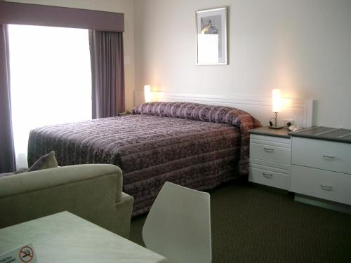 マクラーレン・ヴェイルにあるMcLaren Vale Motel & Apartmentsのベッド、デスク、椅子が備わるホテルルームです。