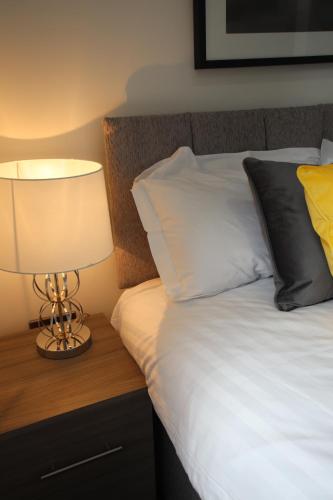 a bed with white sheets and a lamp on a night stand at Halifax House, Studio Apartment 213 in Halifax