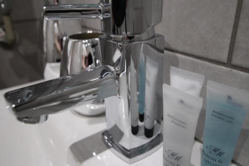 a silver toothbrush holder sitting on a bathroom sink at Halifax House, Studio Apartment 213 in Halifax