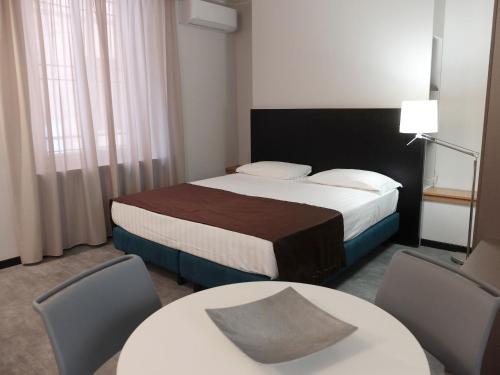 a hotel room with a bed and two tables and chairs at Hotel Carlton in Ferrara