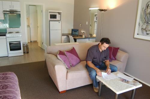 a man sitting on a couch in a living room at McLaren Vale Motel & Apartments in McLaren Vale
