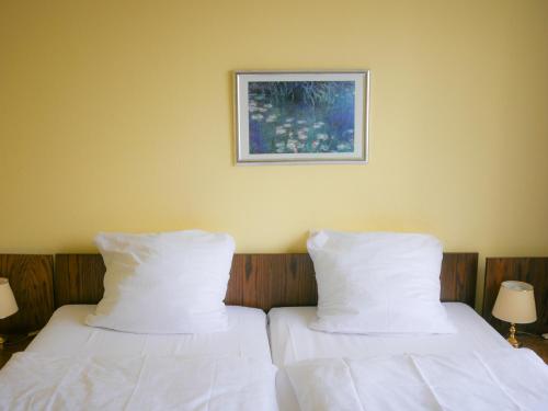 two beds with white sheets and a picture on the wall at Hotel Oronto in Koblenz