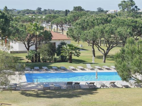 uma vista para uma piscina com espreguiçadeiras e árvores em Spacious Apartment in Quarteira with Swimming Pool em Vilamoura