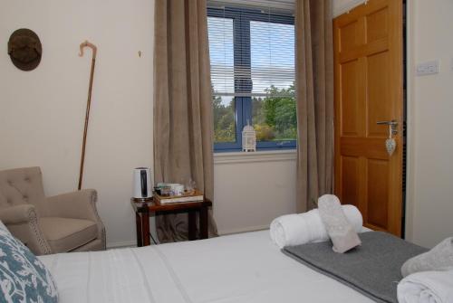 a bedroom with a bed and a chair and a window at Suardal Guest House in Fort Augustus