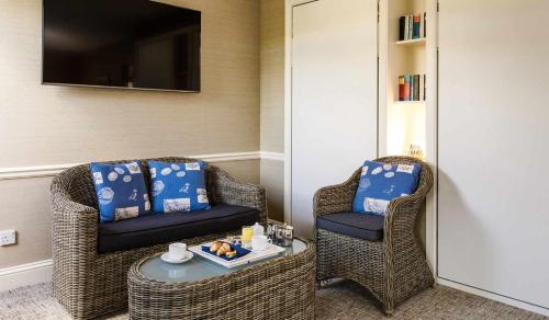 two wicker chairs and a table in a room at Golden Sands in St Brelade