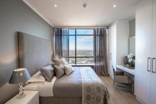 1 dormitorio con 1 cama grande y ventana grande en Masingita Towers Penthouse, en Johannesburgo