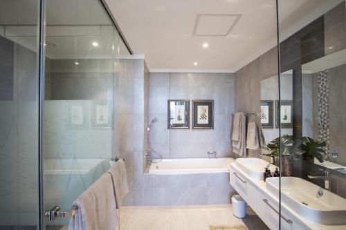 uma casa de banho com uma banheira e um lavatório e uma banheira em Masingita Towers Penthouse em Joanesburgo