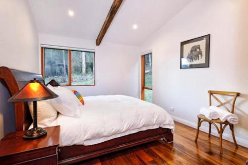 a bedroom with a bed and a lamp on a table at Adventure Bay Retreat Bruny Island in Adventure Bay