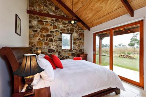 1 dormitorio con 1 cama grande y pared de piedra en Adventure Bay Retreat Bruny Island, en Adventure Bay