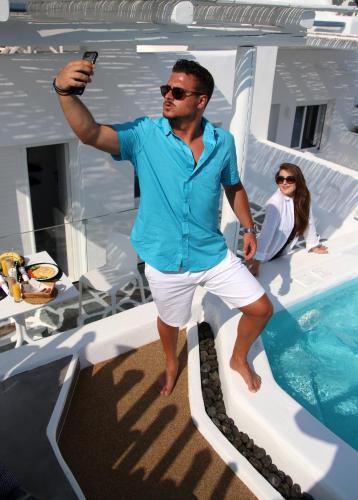 a man holding a cell phone while standing on a boat at Annio studios in Plaka