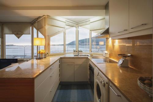 eine Küche mit einer Spüle und einer Theke mit Fenstern in der Unterkunft Labrax Viewpoint in Caminha