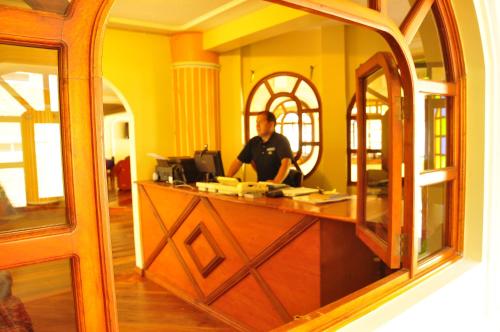 a man is standing at a counter in a room at Hotel Donde Marcelo in Baños