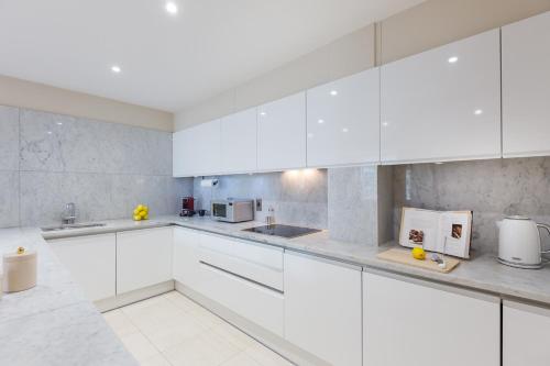 a white kitchen with white cabinets and appliances at Urban Chic - Exeter Street in London