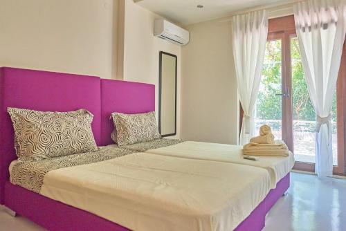 ein großes Bett mit einem lila Kopfteil in einem Zimmer in der Unterkunft Pura Vida in Rodakino