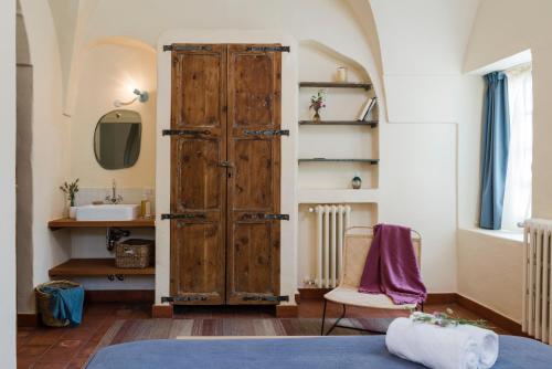 a bedroom with a wooden door and a sink at La Maison des Sources in ‘Ayn Zḩaltā