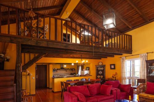 a living room with red couches and a kitchen at Chalet Pico das Pedras in Santana