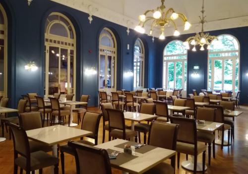 a dining room with tables and chairs and a chandelier at Grand Hotel Regina Salsomaggiore in Salsomaggiore Terme