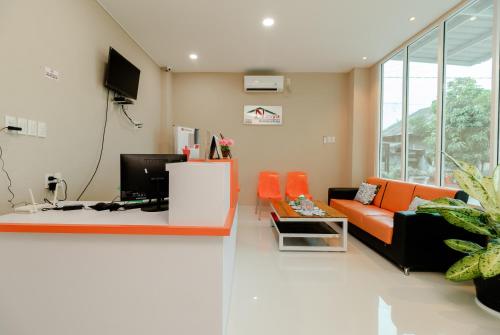 a living room with an orange couch and a tv at RedDoorz Syariah @ Panglima Polem Aceh in Banda Aceh