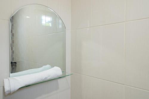 a white bathroom with a mirror and a towel at RedDoorz Syariah @ Panglima Polem Aceh in Banda Aceh