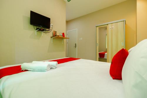 a bedroom with a large white bed with red pillows at RedDoorz Syariah @ Panglima Polem Aceh in Banda Aceh