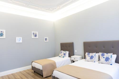 Dos camas en una habitación con paredes blancas. en Apartamentos Castelo, en Póvoa de Varzim