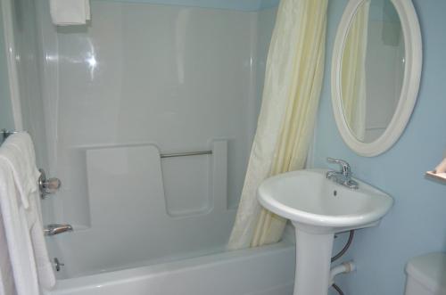 Un baño blanco con lavabo y espejo. en Paramount Motel Pocono, en East Stroudsburg