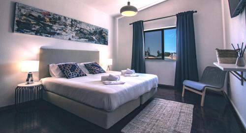 a bedroom with a bed with a window and a chair at Pine House - Faro Airport, Beach and City Center in Faro