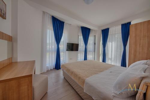 a bedroom with blue curtains and a bed and a television at M Apartments in Bar