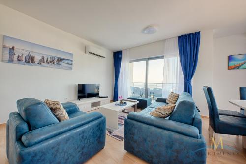 a living room with two blue couches and a television at M Apartments in Bar