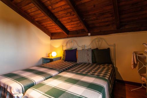 a bedroom with two beds and a wooden ceiling at Chalet Pico das Pedras in Santana