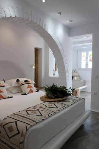a white bedroom with a bed with an archway at Annio studios in Plaka