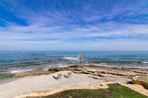 two chairs sitting on a beach with an umbrella at Almirikia in Pigianos Kampos