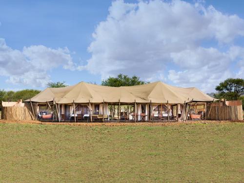 
people sitting under umbrellas on a grassy field at One Nature Nyaruswiga Serengeti in Banagi
