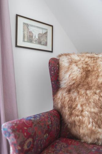 a couch with a furry pillow and a picture on the wall at meinsachsenwald forsthaus friedrichsruh in Aumühle