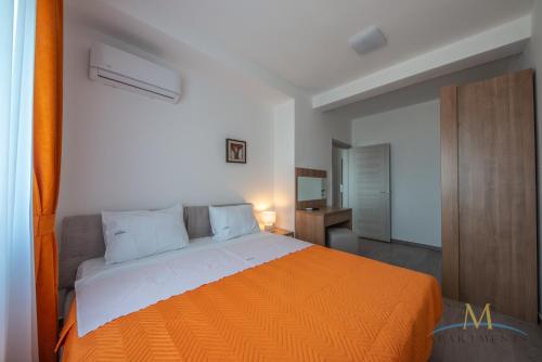 a bedroom with a large bed with an orange blanket at M Apartments in Bar