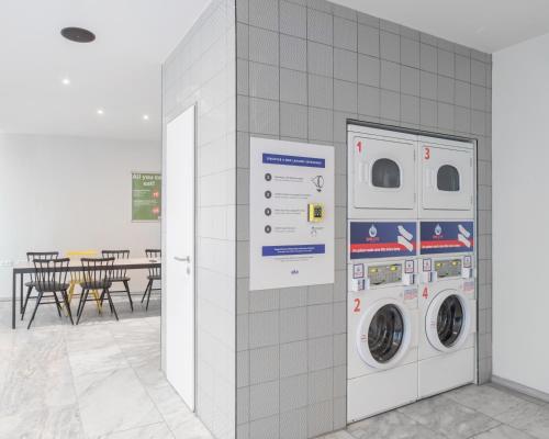 a washing machine and a washer and dryer against a wall at a&o Köln Neumarkt in Cologne