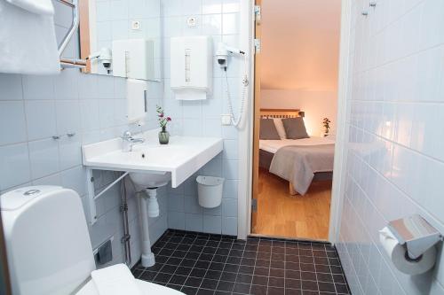a bathroom with a sink and a toilet and a bed at STF Hotel Zinkensdamm in Stockholm