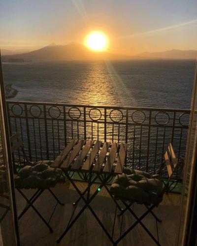 a balcony with a chair and a sunset on the ocean at Lux in Naples