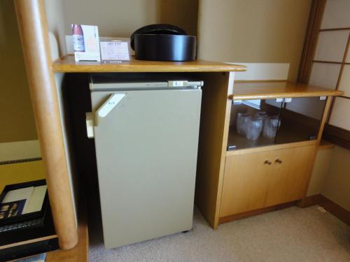 a small refrigerator under a desk with a table at Kasuitei in Yonago