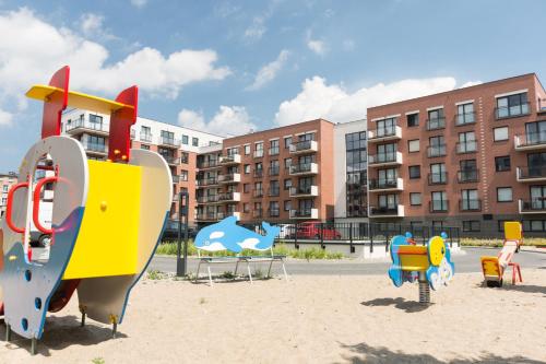 un parque infantil con un colorido equipo de juegos en la arena en D&P Apartments Nowa Grobla, en Gdansk