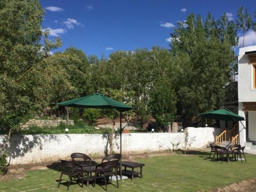 a group of tables and chairs with green umbrellas at Hotel Rezang-La in Leh