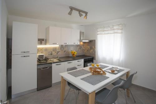 a kitchen with white cabinets and a table with chairs at Spartion Marine in Split