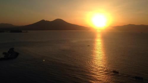 a sunset over the water with mountains in the background at Lux in Naples