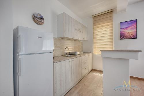 a kitchen with white cabinets and a white refrigerator at M Apartments in Bar
